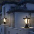 Black square craftsman solar pillar light glowing warm white on a gate post at dusk outside a modern home