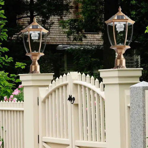 Vintage bronze solar pillar lights, set of two, on gate posts at dusk